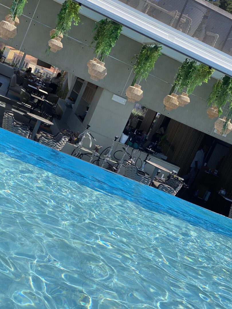 Outdoor pool area with hanging plants and seating under a shaded patio.