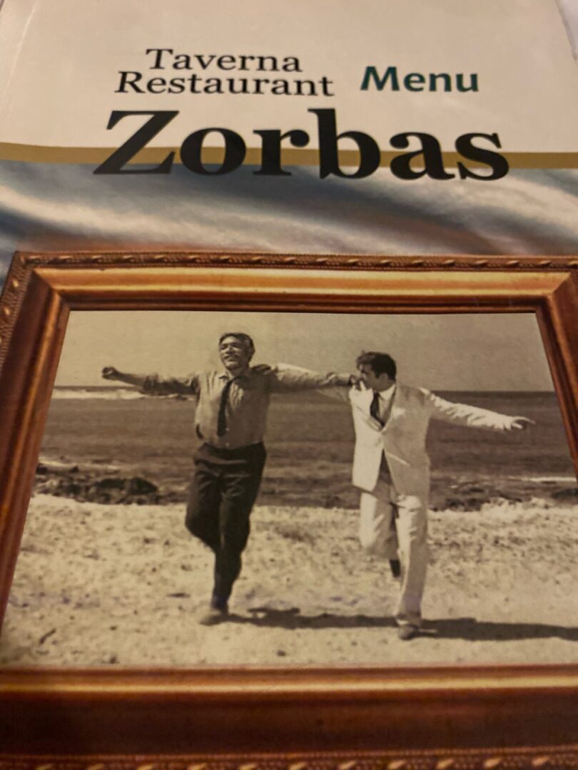 Two men dancing outdoors near the sea in a black and white photo.