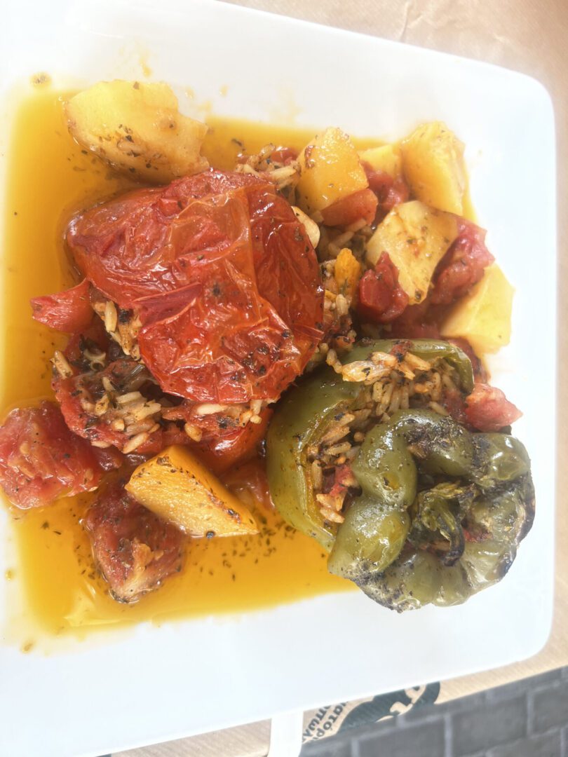 A plate with stuffed bell peppers and roasted potatoes in sauce.
