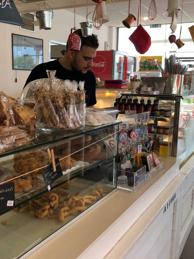 A man behind the counter in a cozy bakery with various baked goods on display.