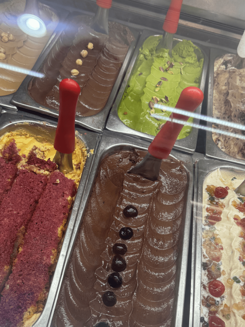 Variety of colorful gelato flavors in a display case with spoons.