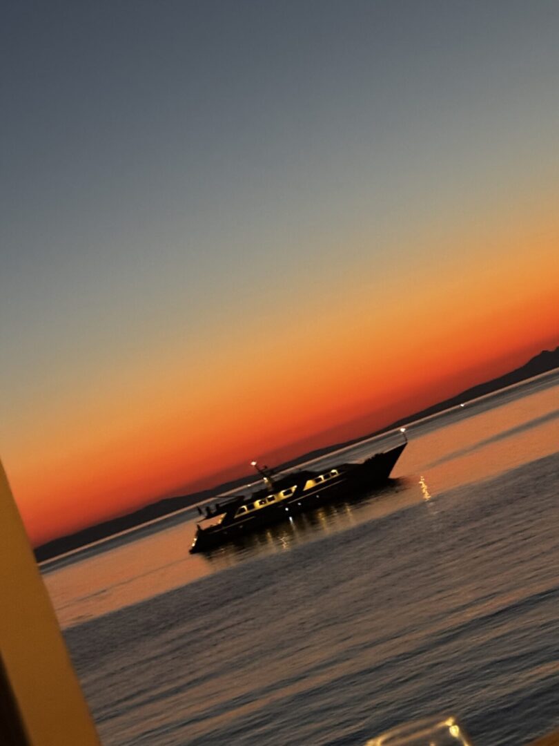 Boat sailing on calm water during a vibrant sunset.
