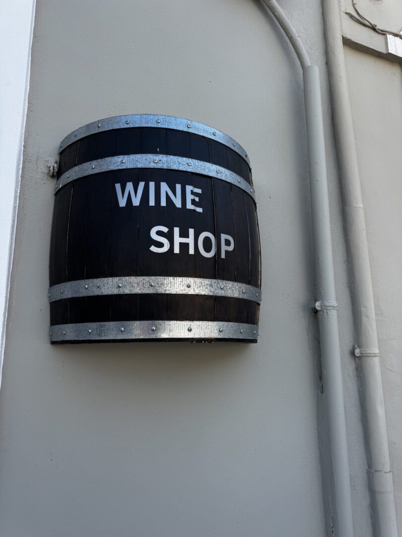 A black and white sign reading 'WINE SHOP' mounted on a gray wall.