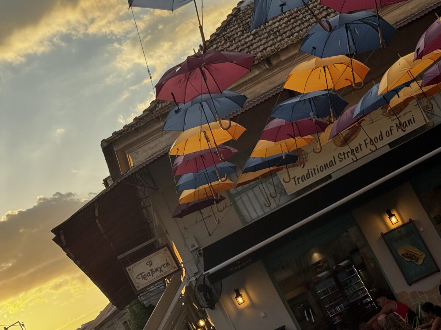Colorful umbrellas hanging above a street at sunset.