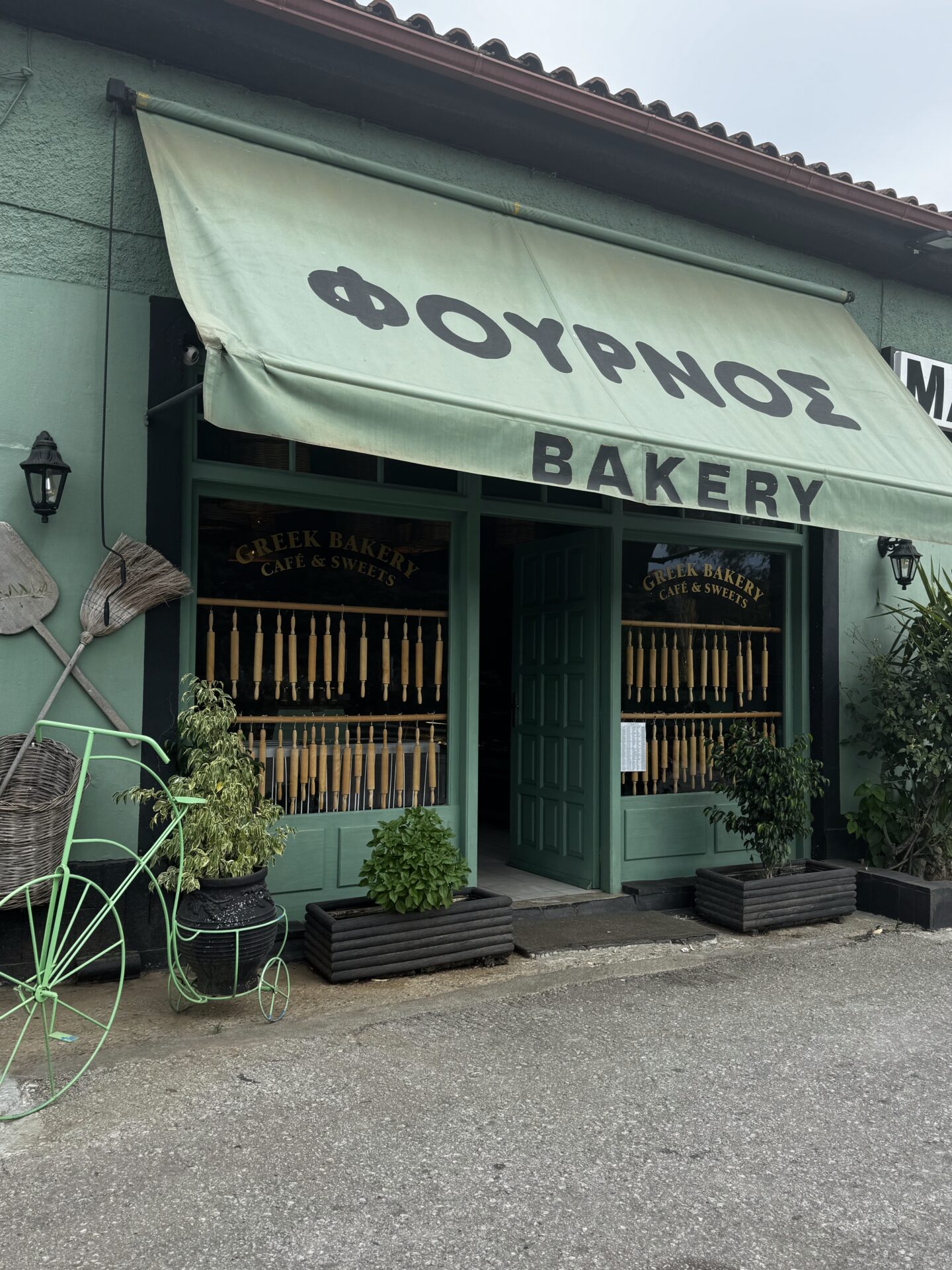 Charming bakery storefront with Greek signage and green accents.