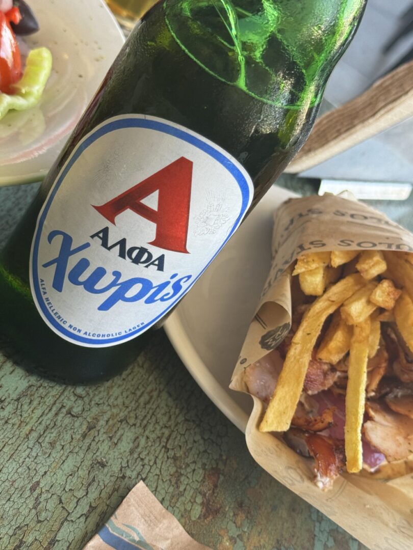 A bottle of Ambar beer with a bowl of fries and bacon on a wooden table.
