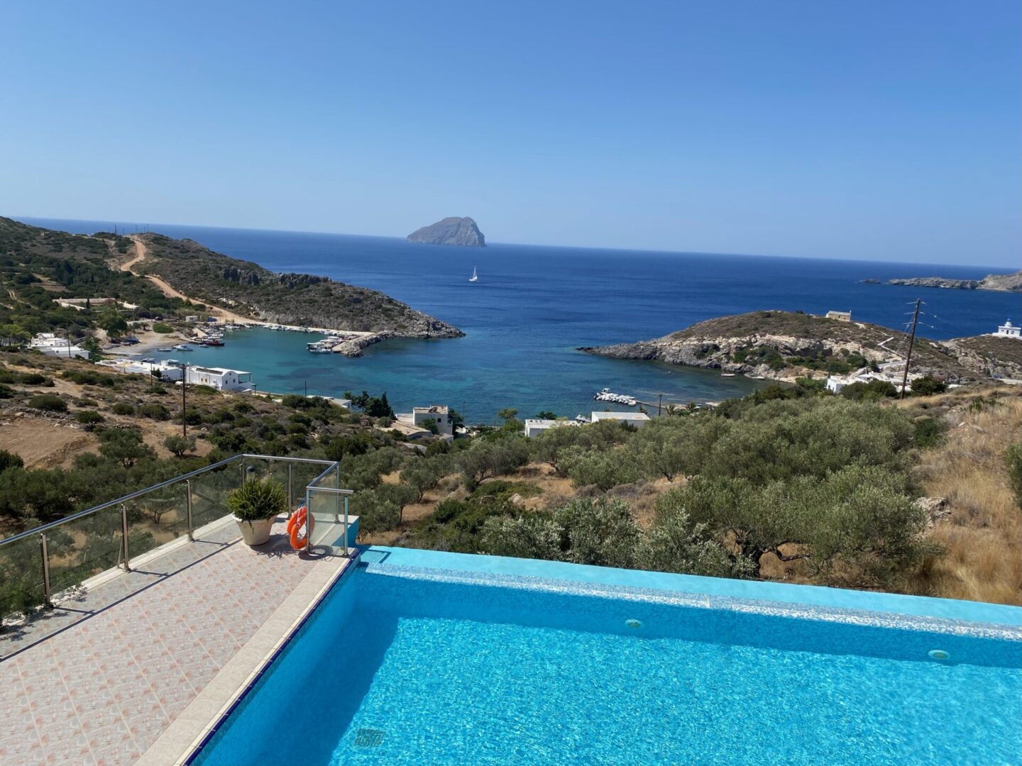 Scenic coastal view with a clear blue pool overlooking the sea and rocky islands.