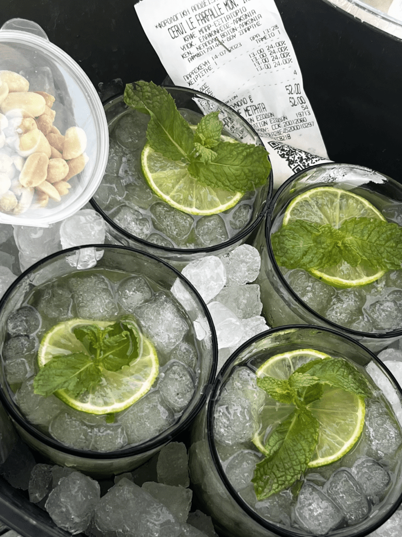 Four glasses with ice and lime slices on a white tray.
