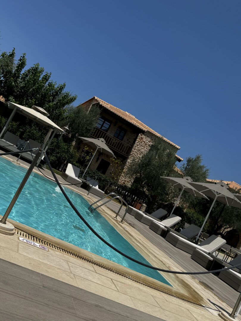 Relaxing poolside area with sun umbrellas and clear blue sky.