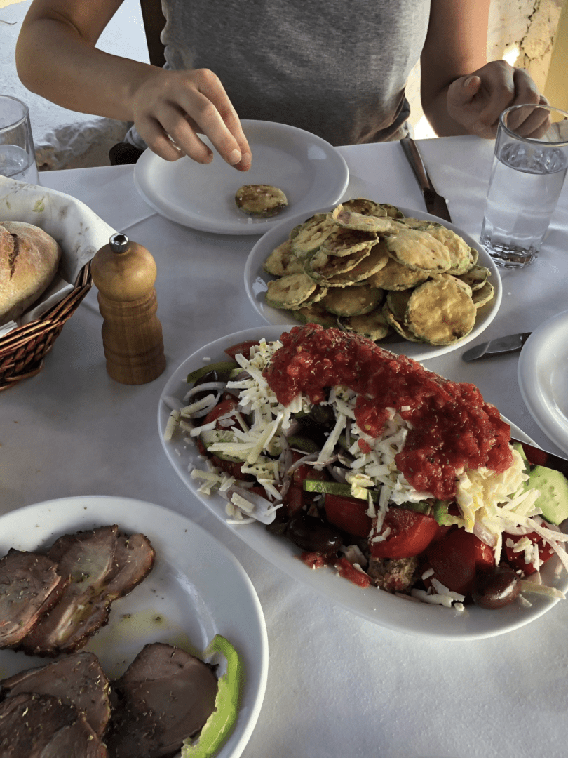 A table with plates of food including fried items, a red sauced dish, and bread.
