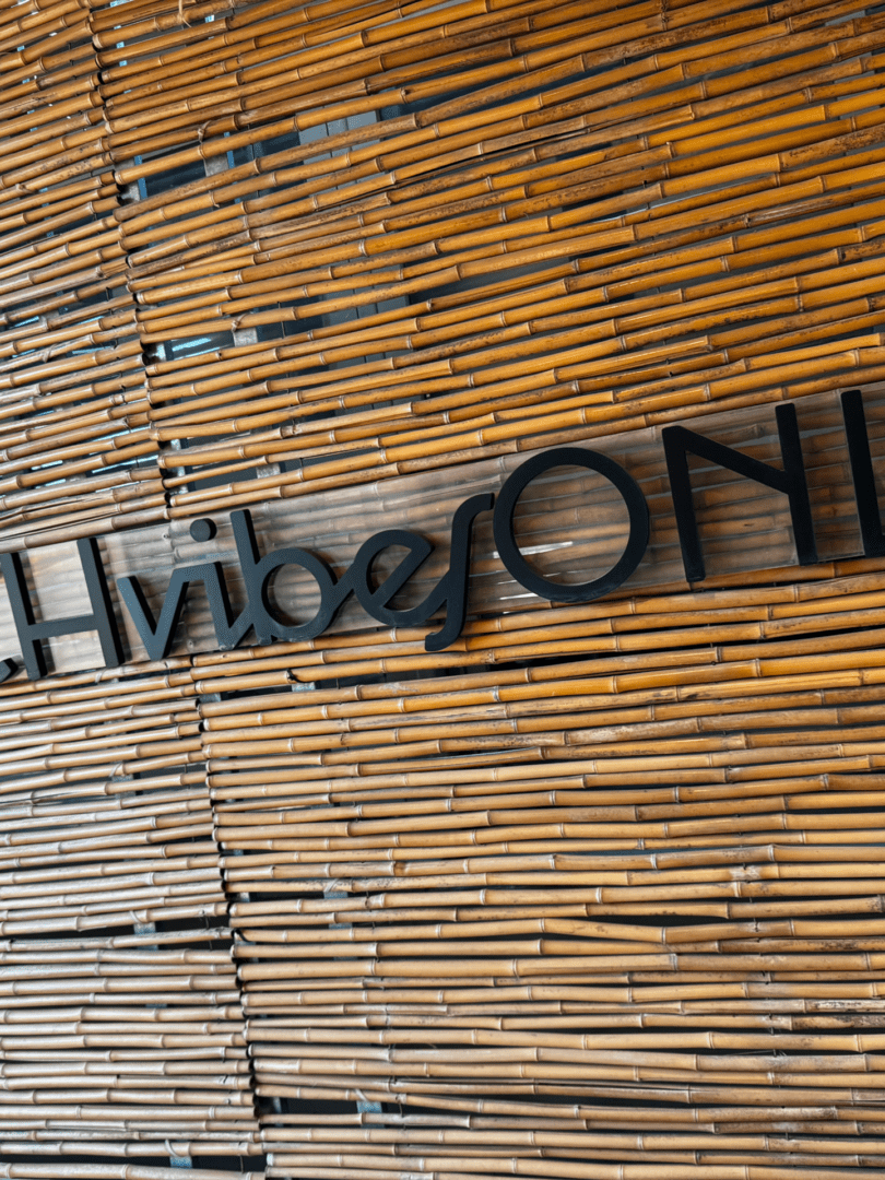 Black text 'Vibes ONLY' on a bamboo wall.