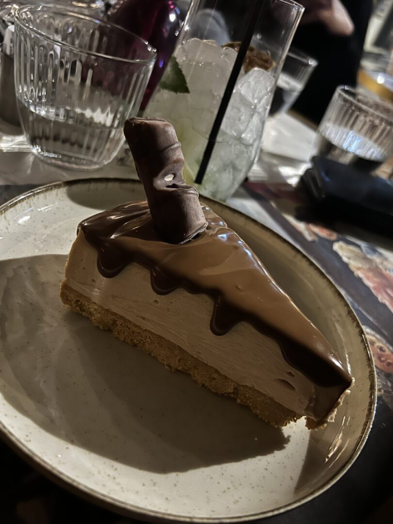 Delicious slice of chocolate-topped cheesecake on a plate.