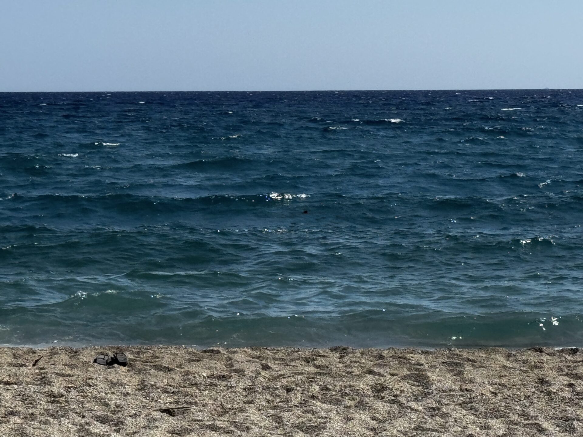 Calm ocean waves meeting the sandy beach under a clear sky.