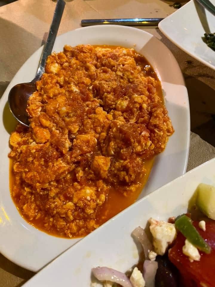 Spicy scrambled eggs in a rich tomato sauce on a white plate.